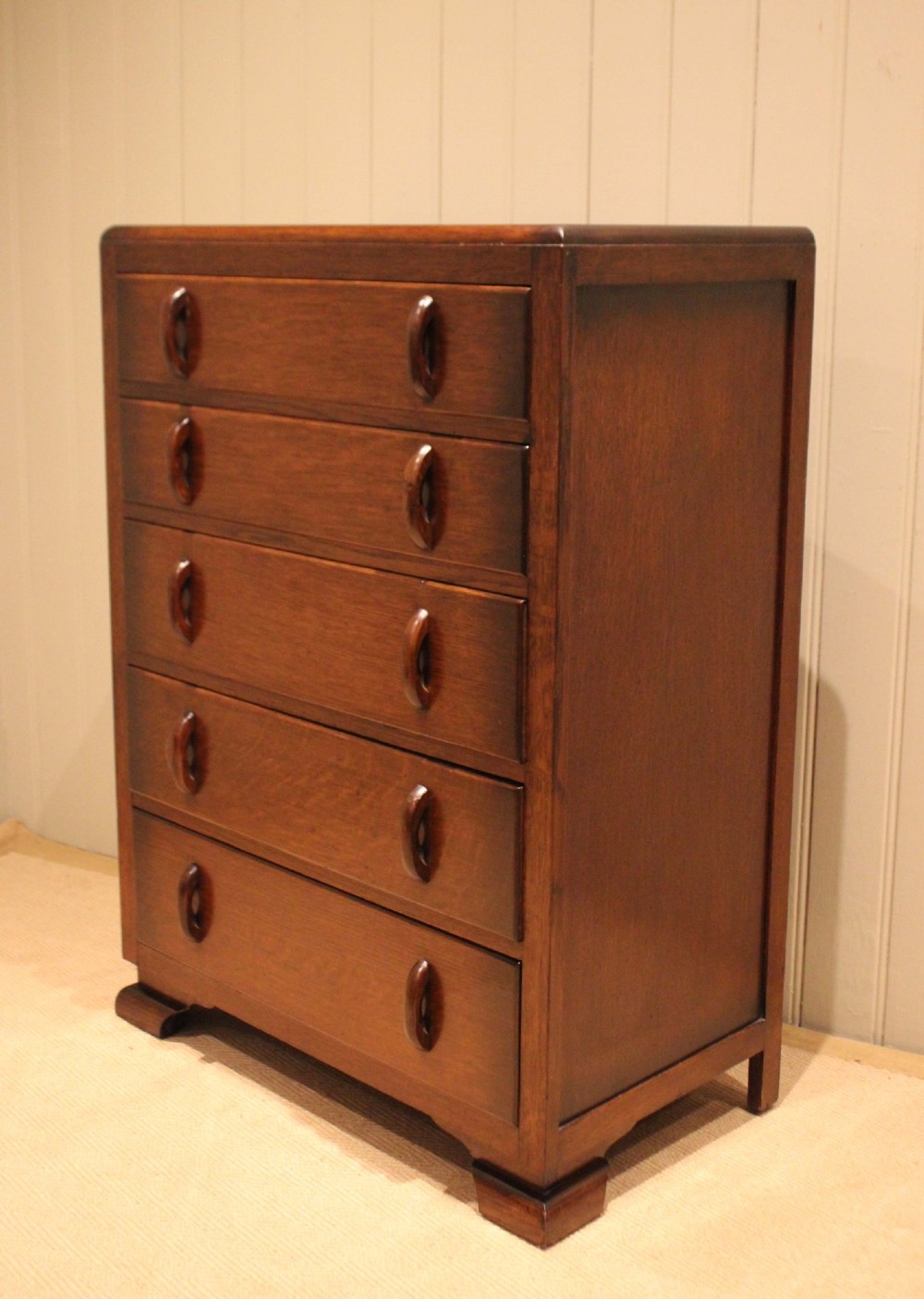 A dark brown oak Art Deco chest of drawers featuring five stacked drawers with matching wood handles and stepped feet. View VIII