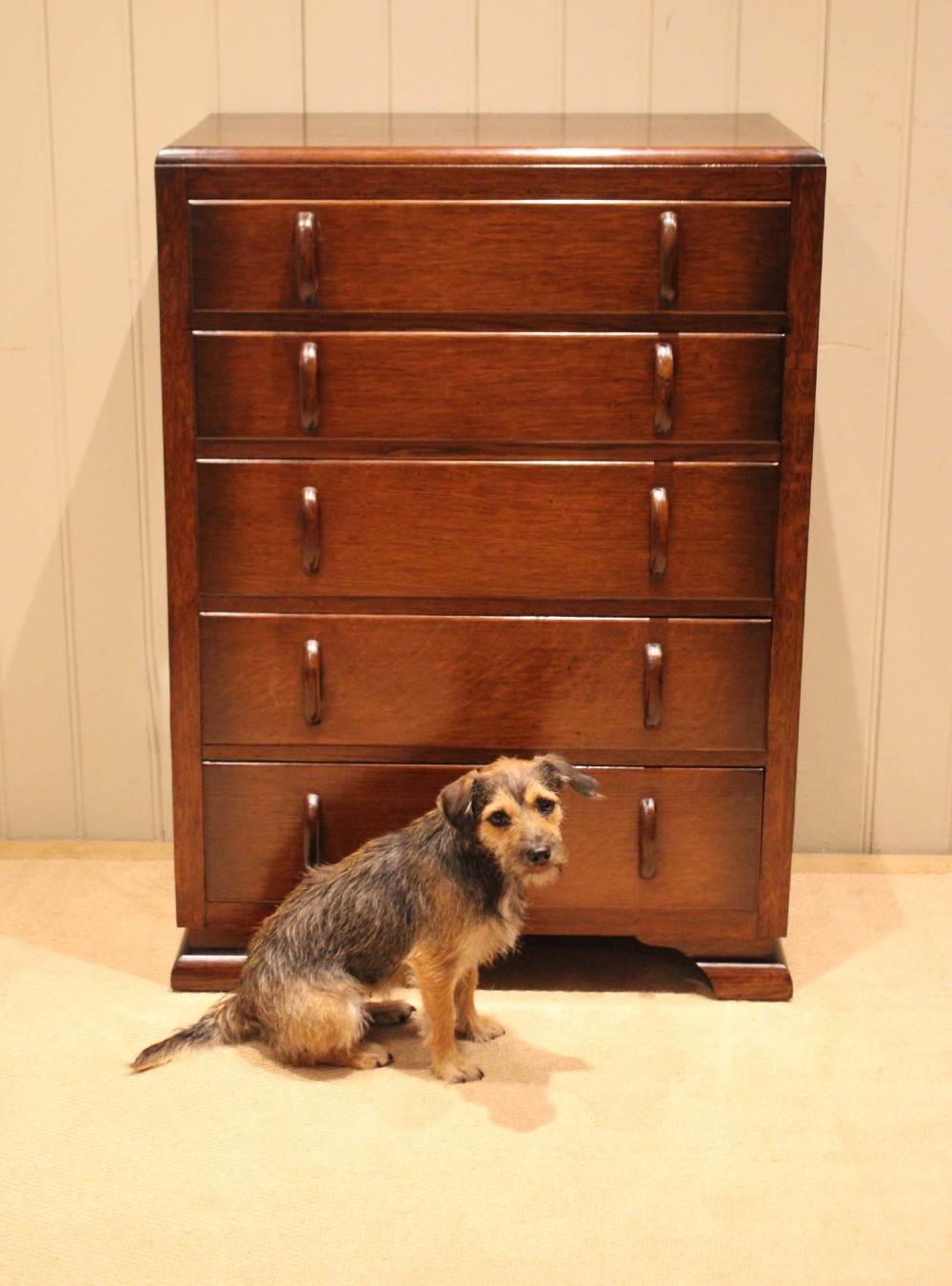 A dark brown oak Art Deco chest of drawers featuring five stacked drawers with matching wood handles and stepped feet. View IX