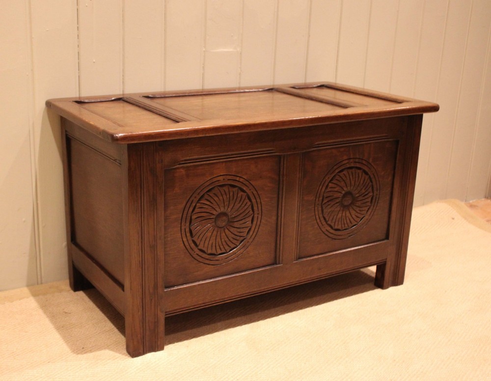 A dark brown carved oak coffer featuring a three-panel lid and two front panels carved with circular rosette motifs. View II