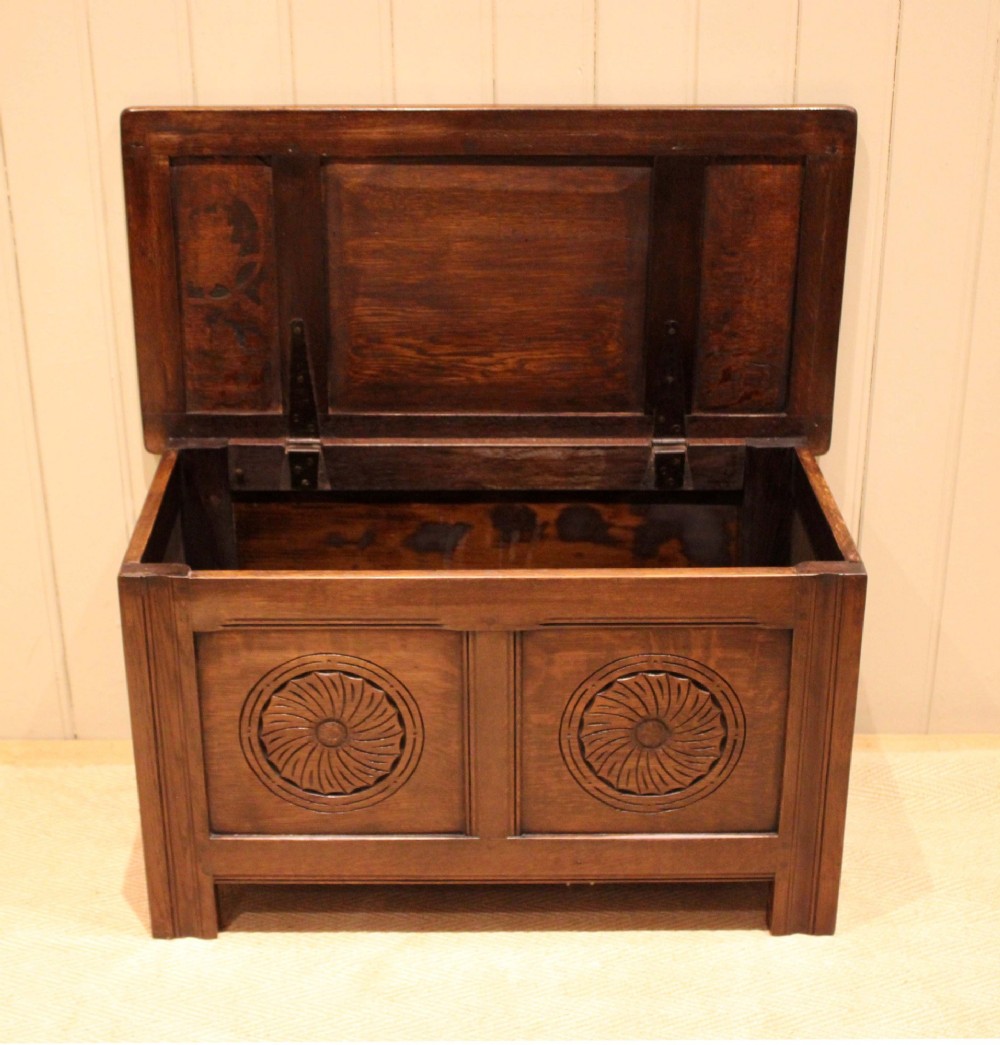 A dark brown carved oak coffer featuring a three-panel lid and two front panels carved with circular rosette motifs. View VII