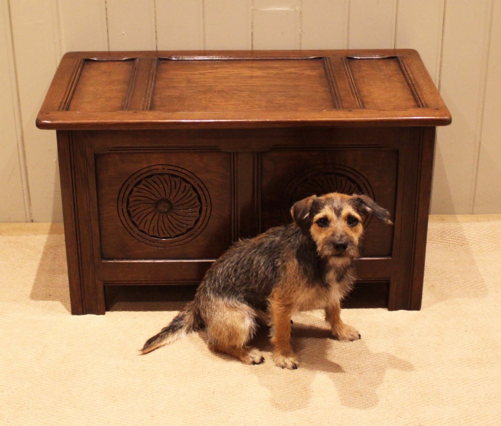 A dark brown carved oak coffer featuring a three-panel lid and two front panels carved with circular rosette motifs. View VIII