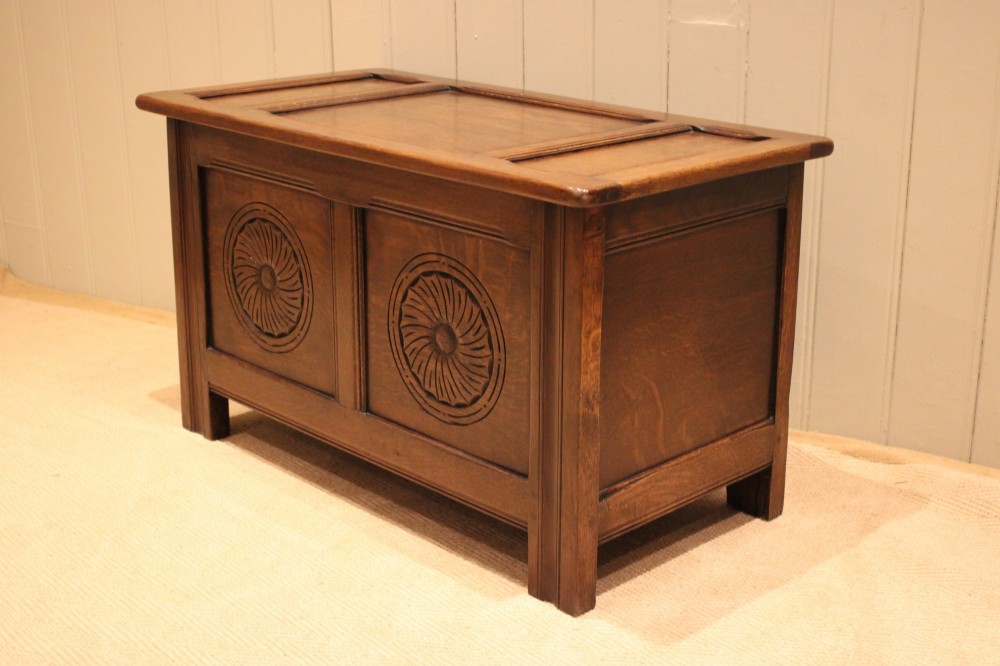 A dark brown carved oak coffer featuring a three-panel lid and two front panels carved with circular rosette motifs. View IX
