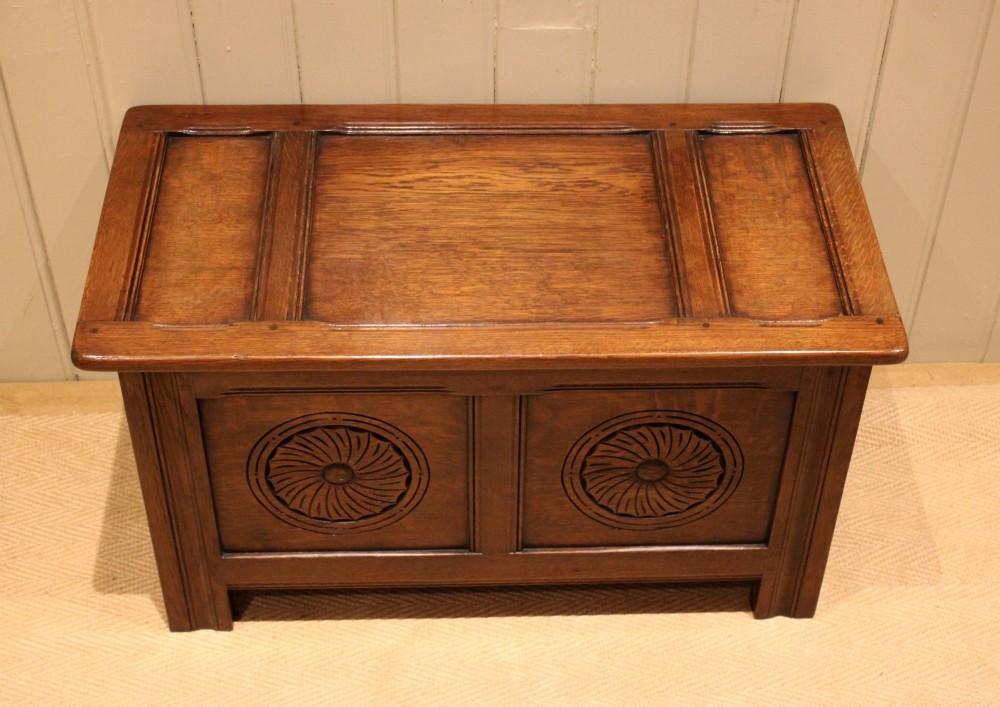 A dark brown carved oak coffer featuring a three-panel lid and two front panels carved with circular rosette motifs. View XI