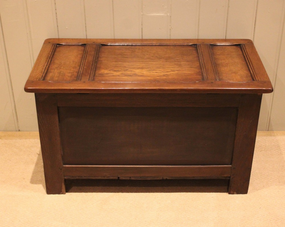A dark brown carved oak coffer featuring a three-panel lid and two front panels carved with circular rosette motifs. View XII