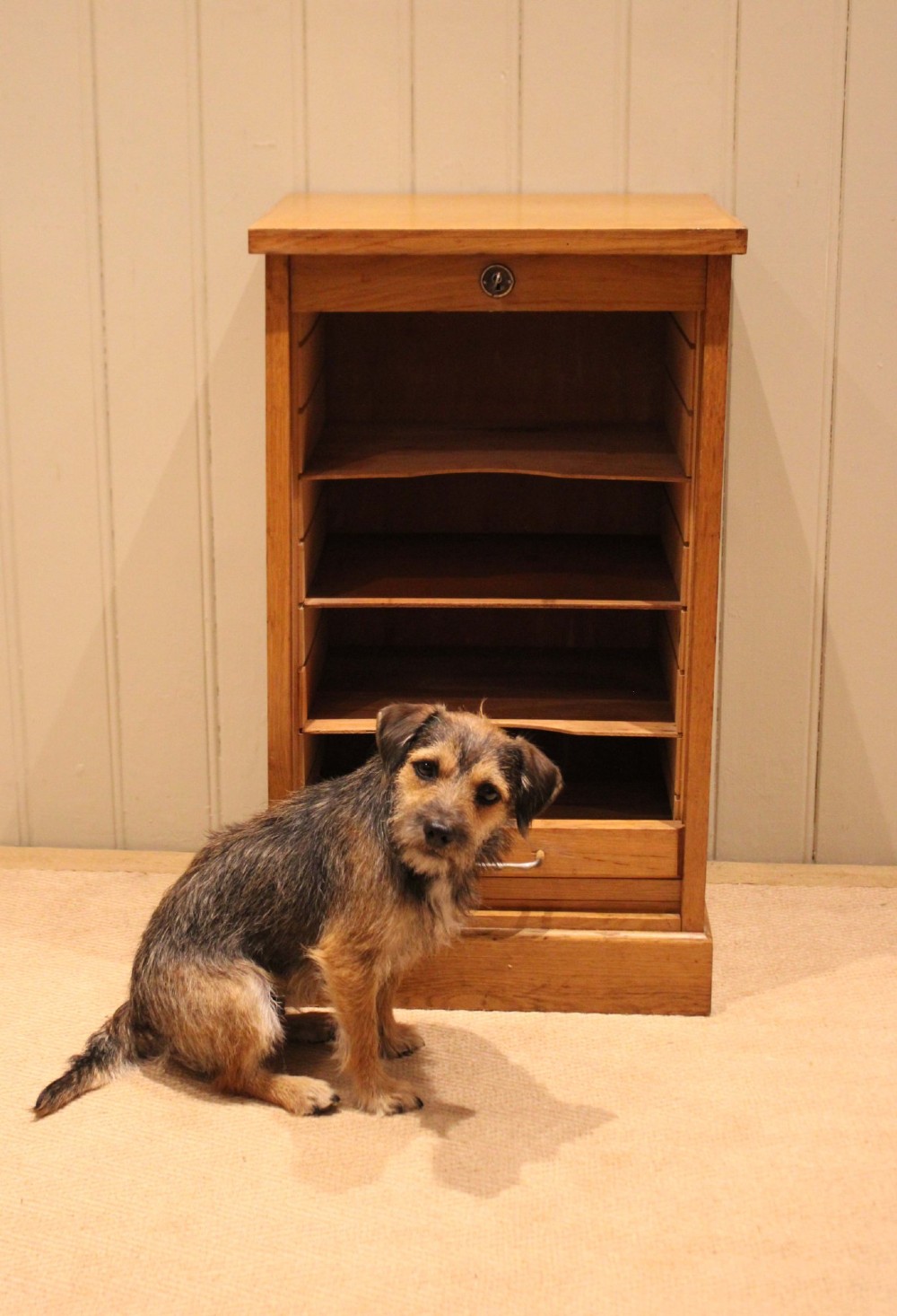 A small light oak filing cabinet featuring a slatted wooden tambour front with a metal handle and keyhole lock at the top. View VIII