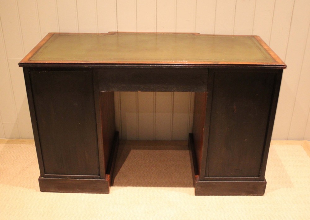 A walnut breakfront pedestal desk featuring nine drawers with brass handles and a green leather writing insert set into the top surface. View XII