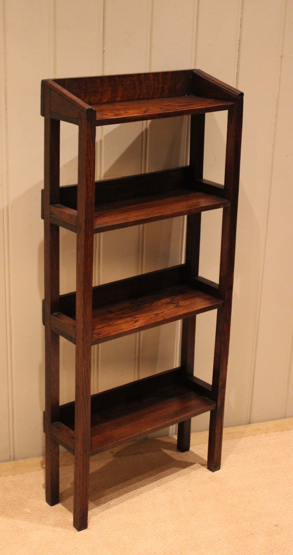 A tall, narrow Edwardian dark oak open-back bookcase featuring four horizontal shelves and straight square legs. View II