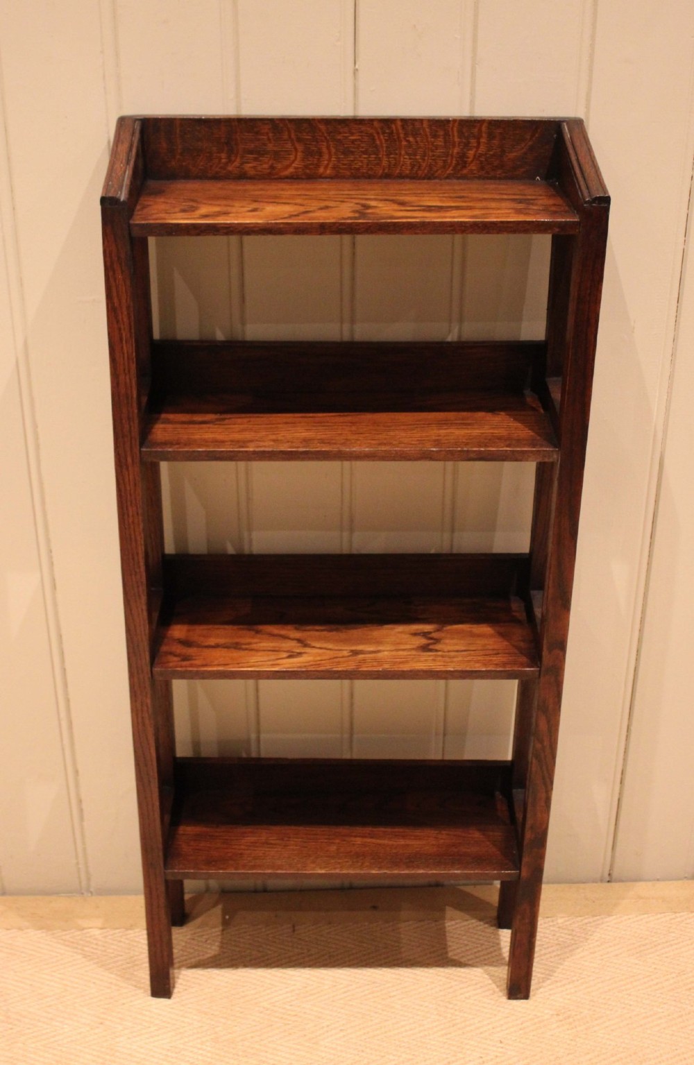 A tall, narrow Edwardian dark oak open-back bookcase featuring four horizontal shelves and straight square legs. View VI