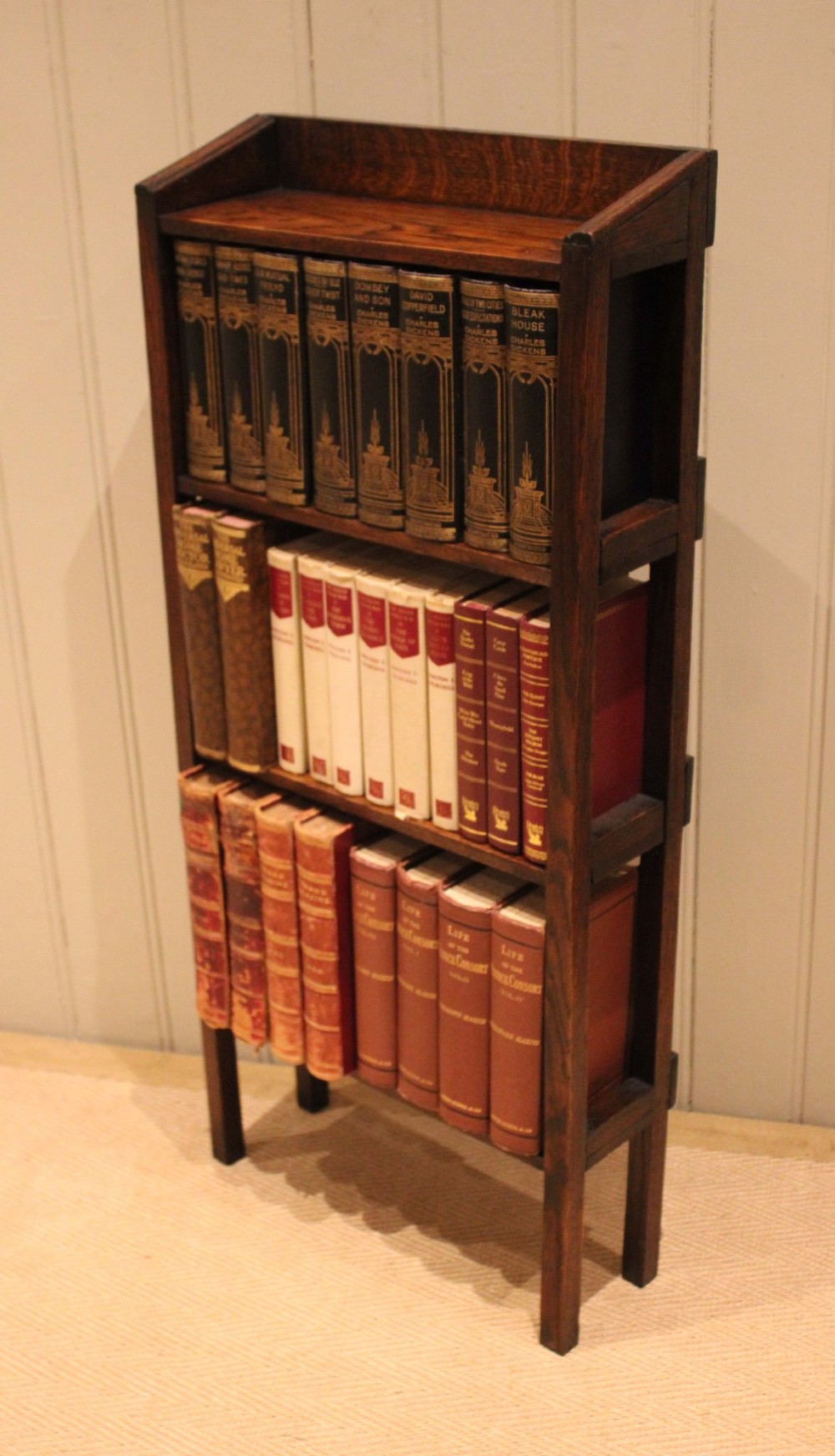A tall, narrow Edwardian dark oak open-back bookcase featuring four horizontal shelves and straight square legs. View IX