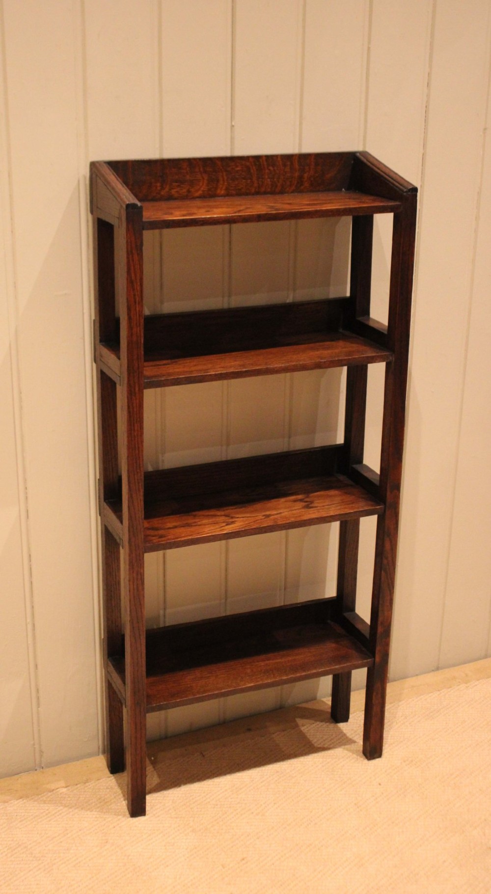 A tall, narrow Edwardian dark oak open-back bookcase featuring four horizontal shelves and straight square legs. View X