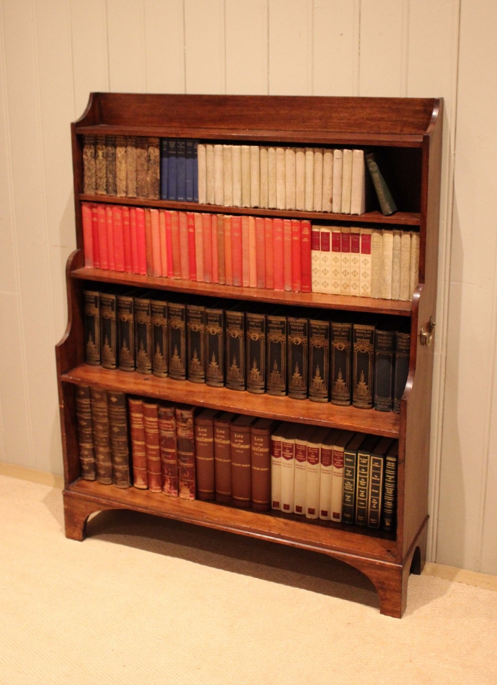 An antique Regency mahogany open bookcase featuring four fixed shelves, graduated side panels, and a shaped apron base. View V