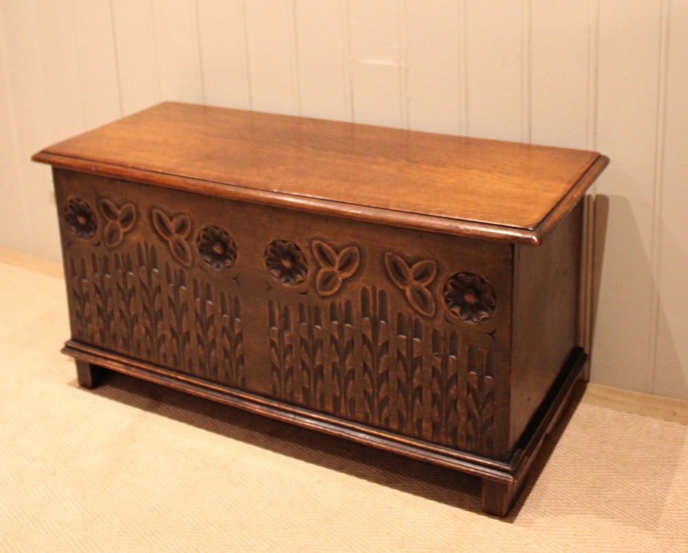 A rectangular solid oak coffer featuring stylized floral and botanical carvings across the front panel with a smooth hinged lid. View VIII