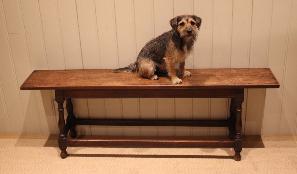 A long solid oak bench featuring a flat timber seat supported by four turned legs and a low rectangular stretcher base. View XI
