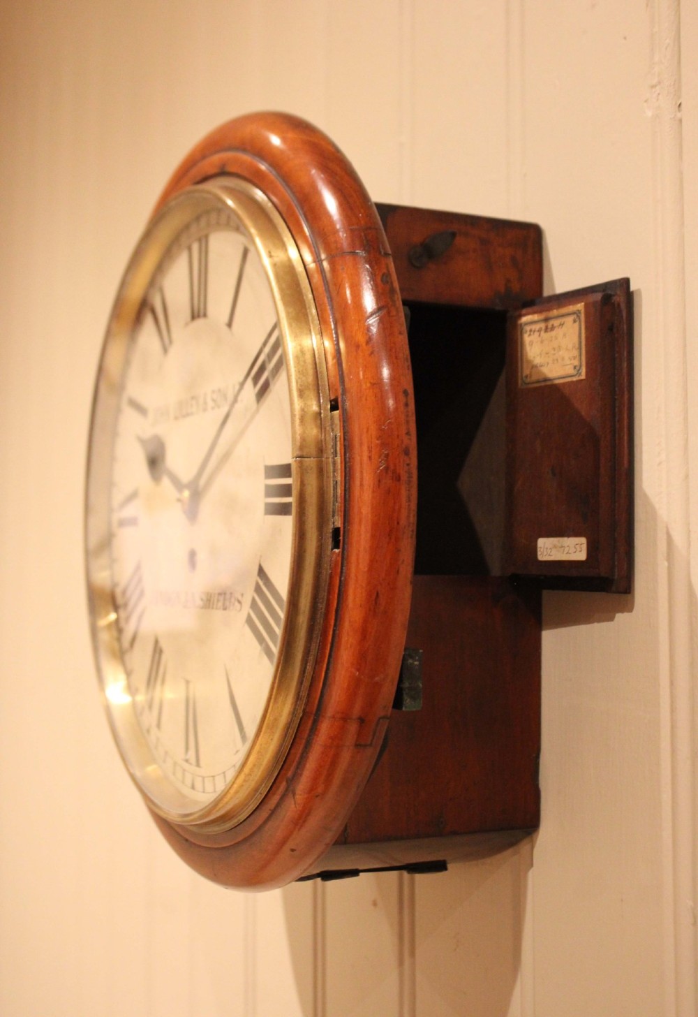A circular late nineteenth-century Victorian wall clock featuring a turned mahogany frame, a polished brass bezel, and a cream dial with black Roman numerals. View VIII