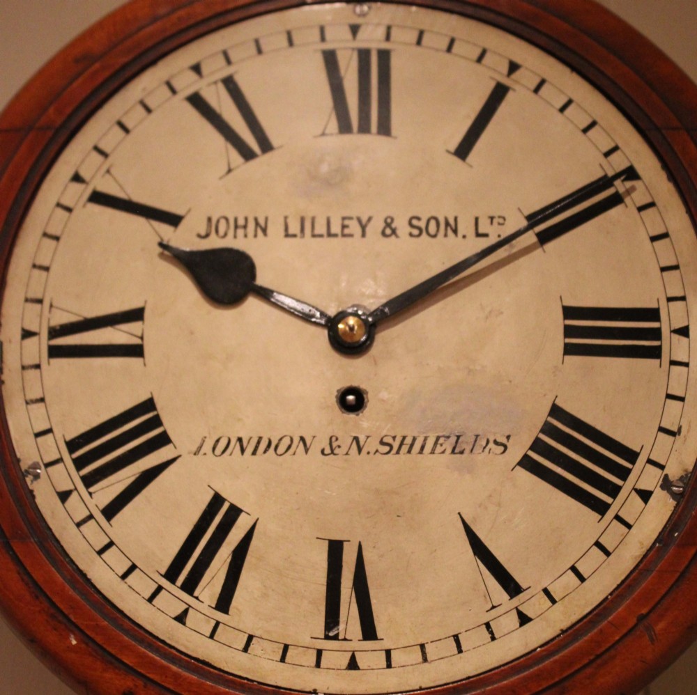 A circular late nineteenth-century Victorian wall clock featuring a turned mahogany frame, a polished brass bezel, and a cream dial with black Roman numerals. View IX