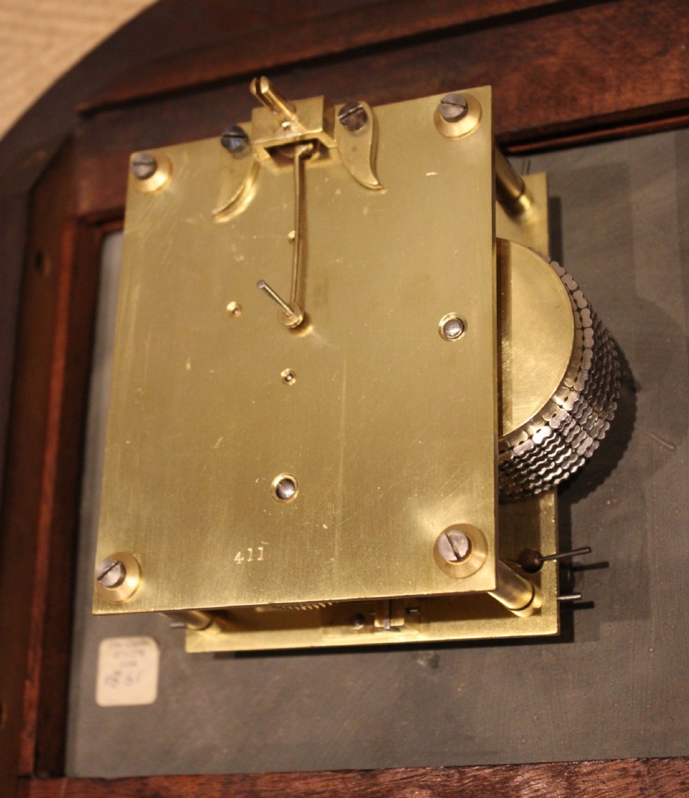 A circular late nineteenth-century Victorian wall clock featuring a turned mahogany frame, a polished brass bezel, and a cream dial with black Roman numerals. View XII