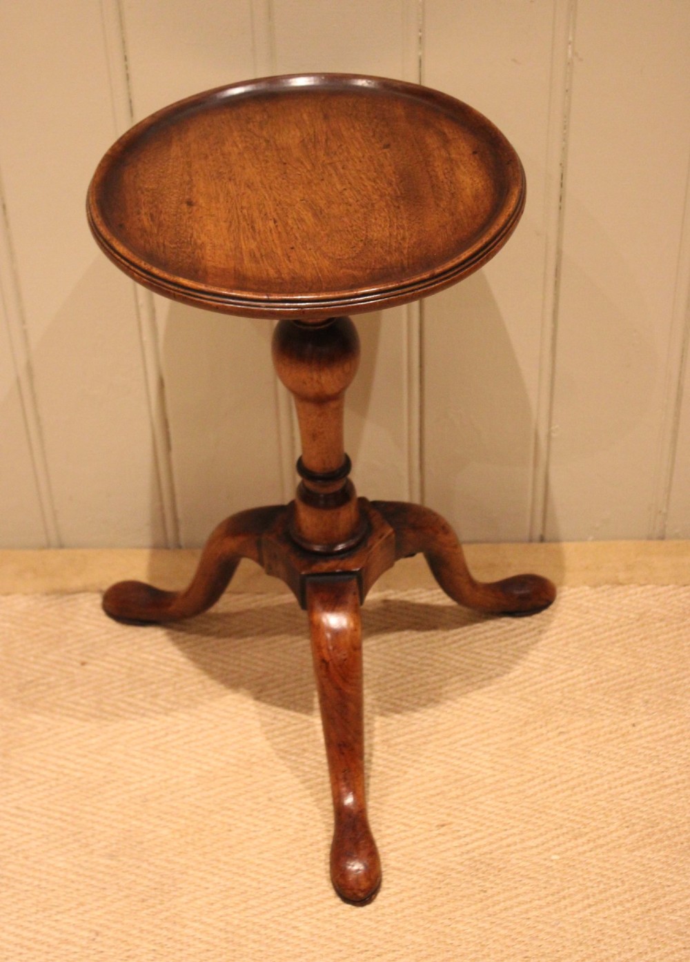 A Georgian mahogany wine table featuring a circular dished top supported by a turned baluster column and tripod pad feet.