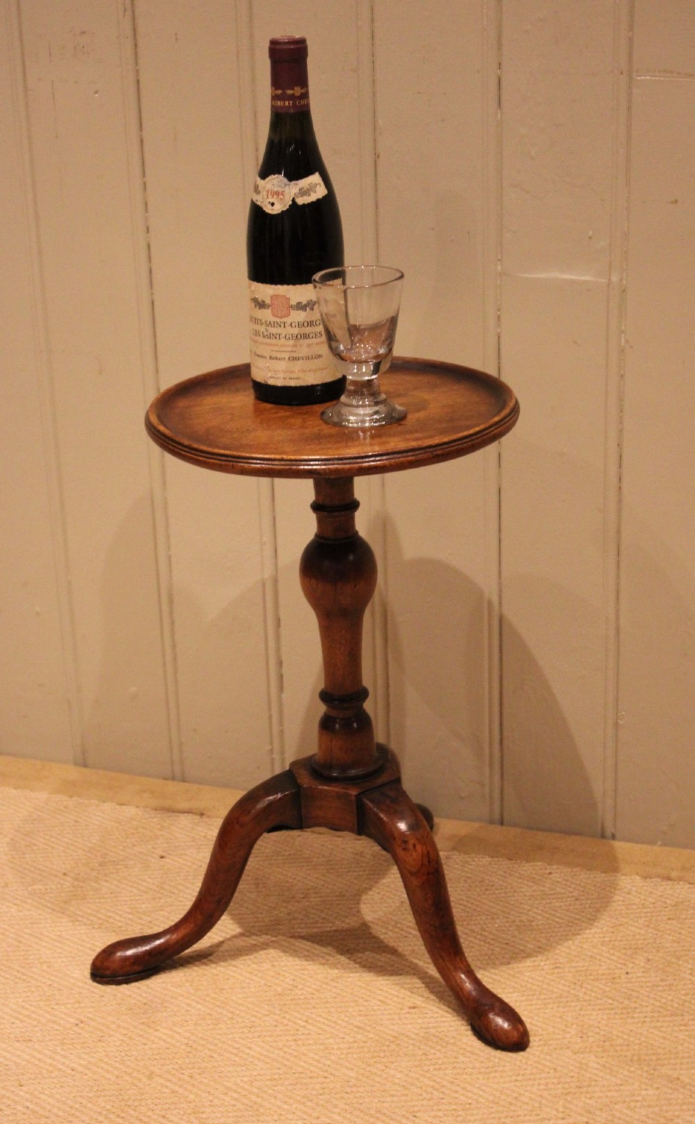 A Georgian mahogany wine table featuring a circular dished top supported by a turned baluster column and tripod pad feet. View II