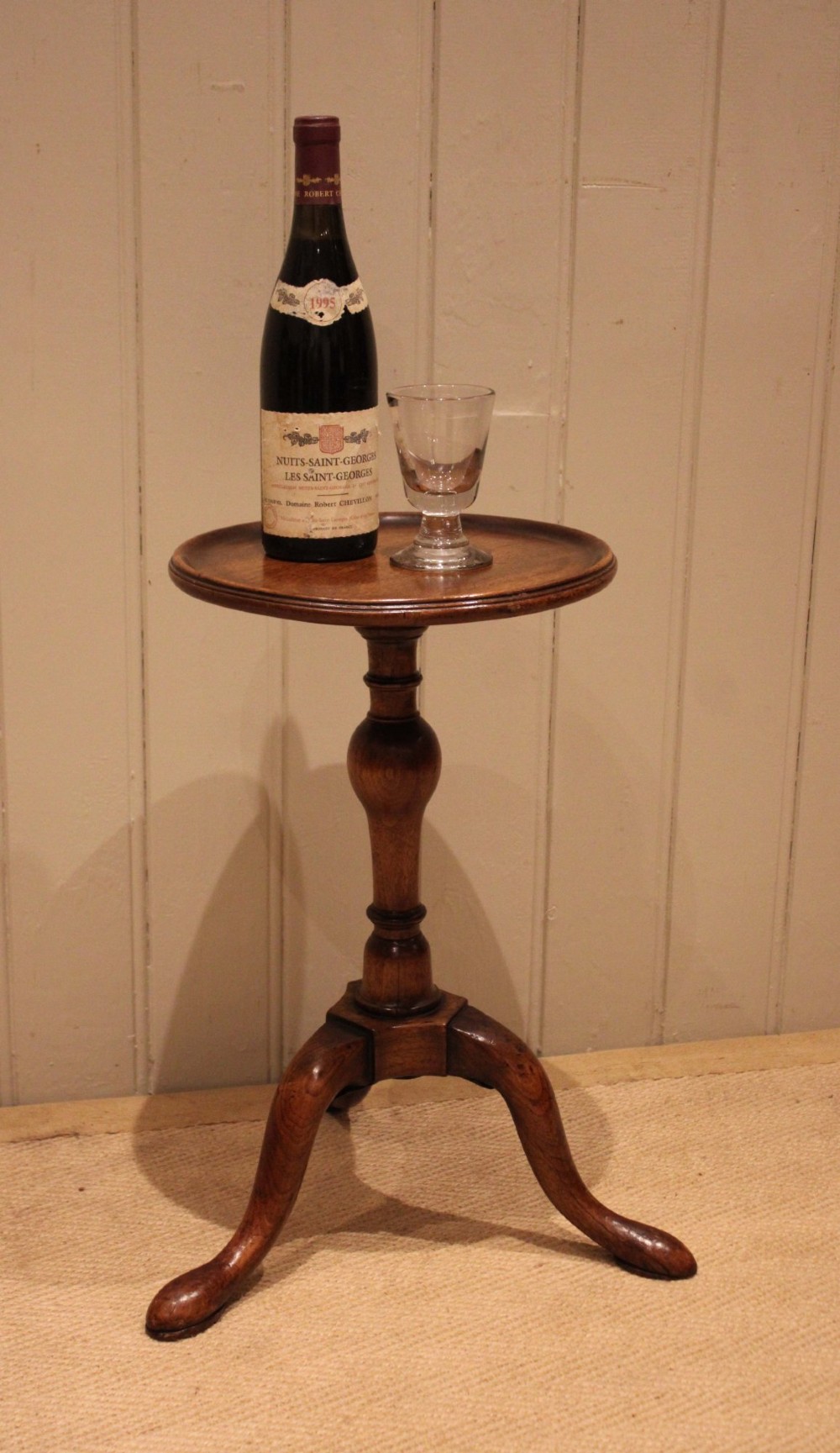 A Georgian mahogany wine table featuring a circular dished top supported by a turned baluster column and tripod pad feet. View V