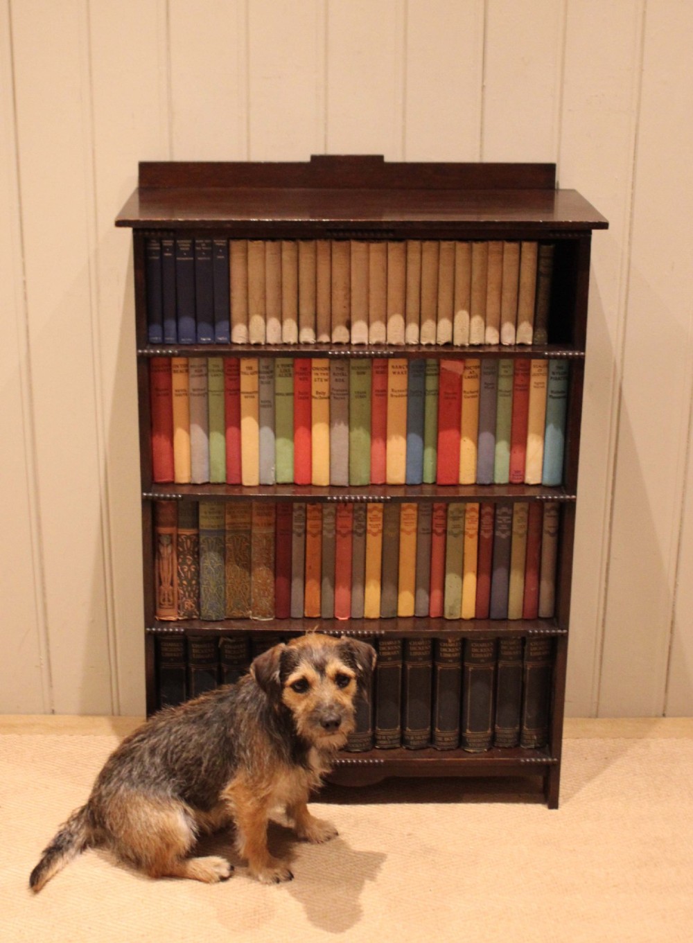 A dark oak open bookcase featuring four horizontal shelves with beaded front edges and a low raised gallery back. View IX