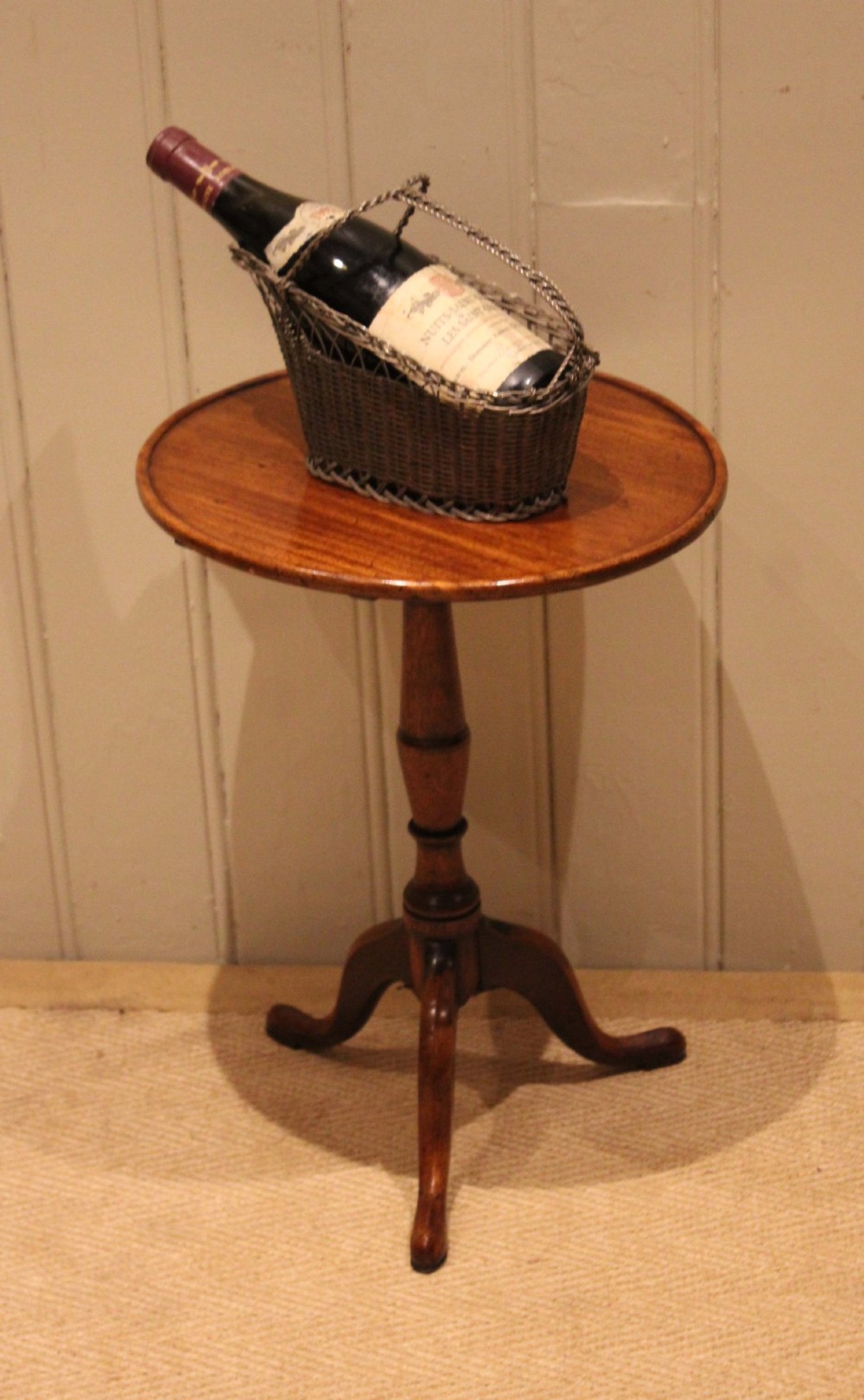 A circular mahogany tilt-top wine table with a turned central pedestal column and a tripod base featuring cabriole legs. View II