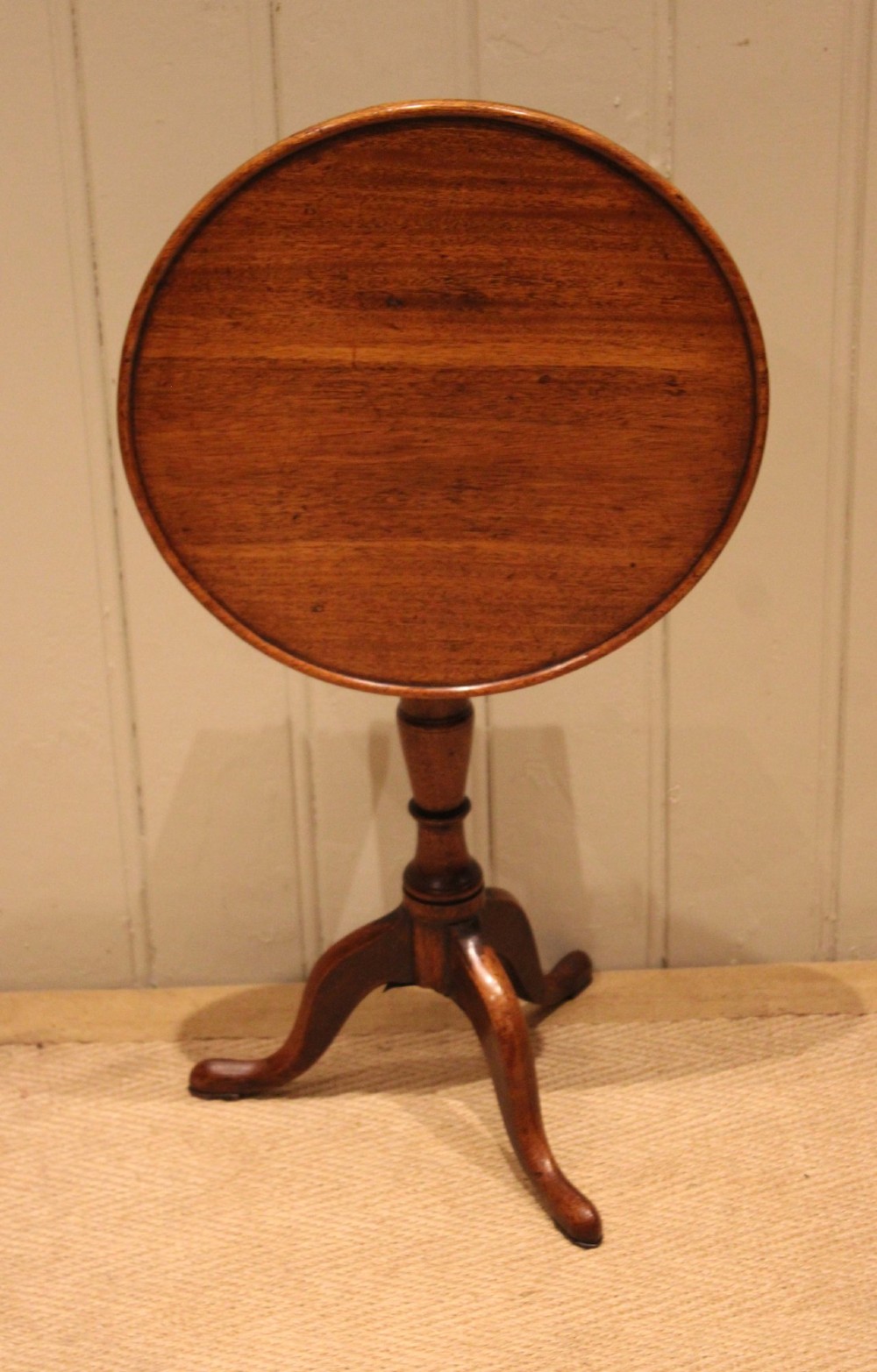 A circular mahogany tilt-top wine table with a turned central pedestal column and a tripod base featuring cabriole legs. View III