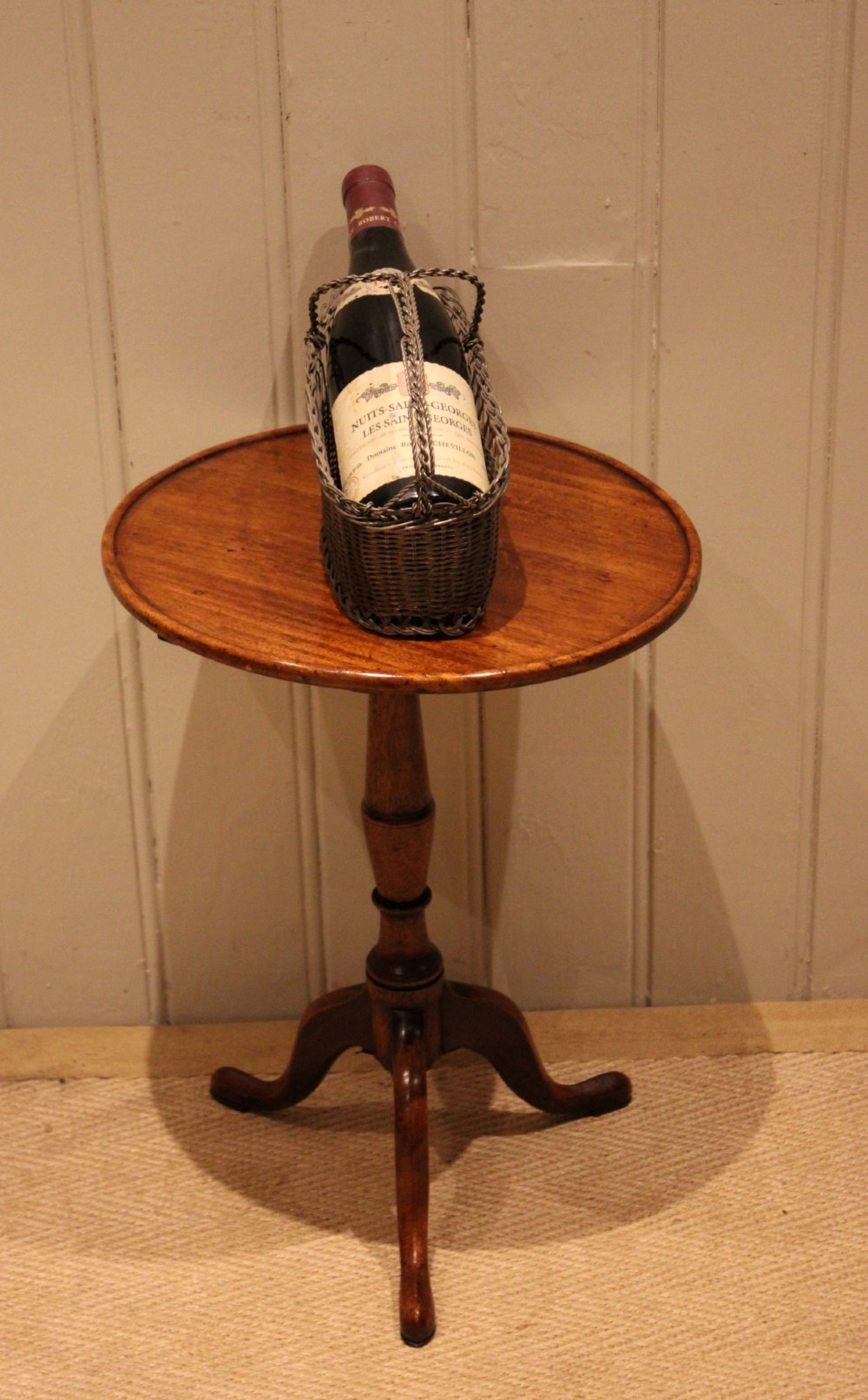 A circular mahogany tilt-top wine table with a turned central pedestal column and a tripod base featuring cabriole legs. View V