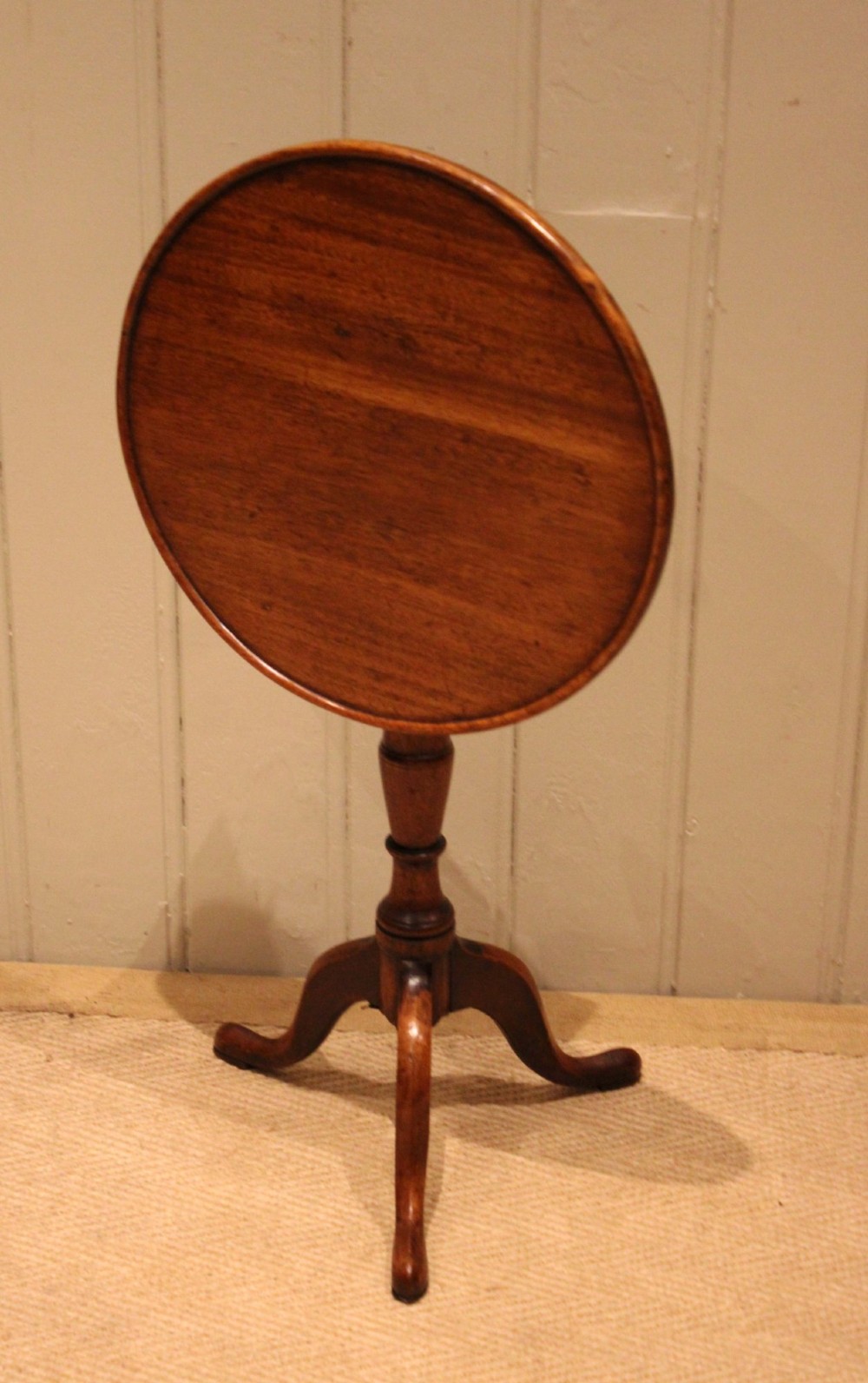 A circular mahogany tilt-top wine table with a turned central pedestal column and a tripod base featuring cabriole legs. View VI