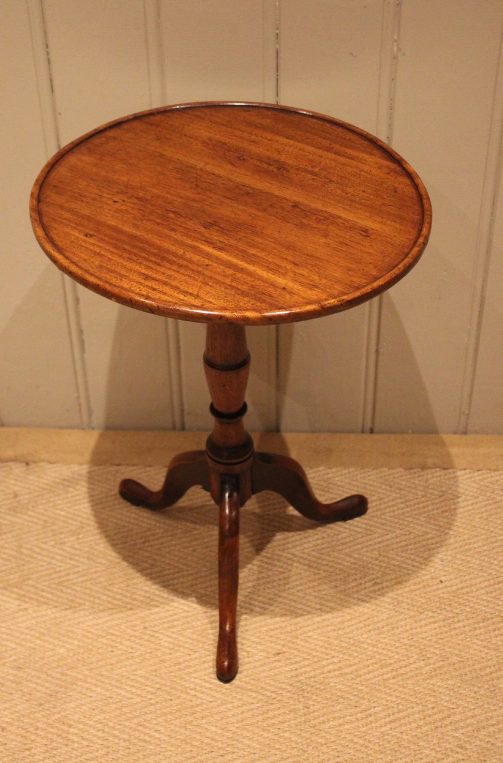 A circular mahogany tilt-top wine table with a turned central pedestal column and a tripod base featuring cabriole legs. View VII