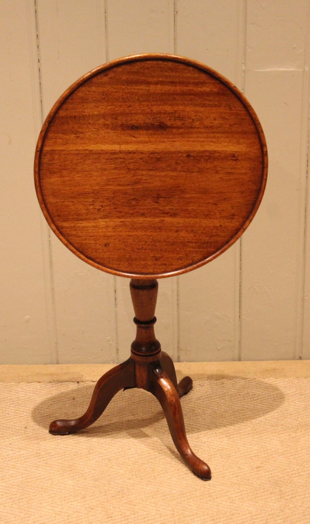 A circular mahogany tilt-top wine table with a turned central pedestal column and a tripod base featuring cabriole legs. View IX