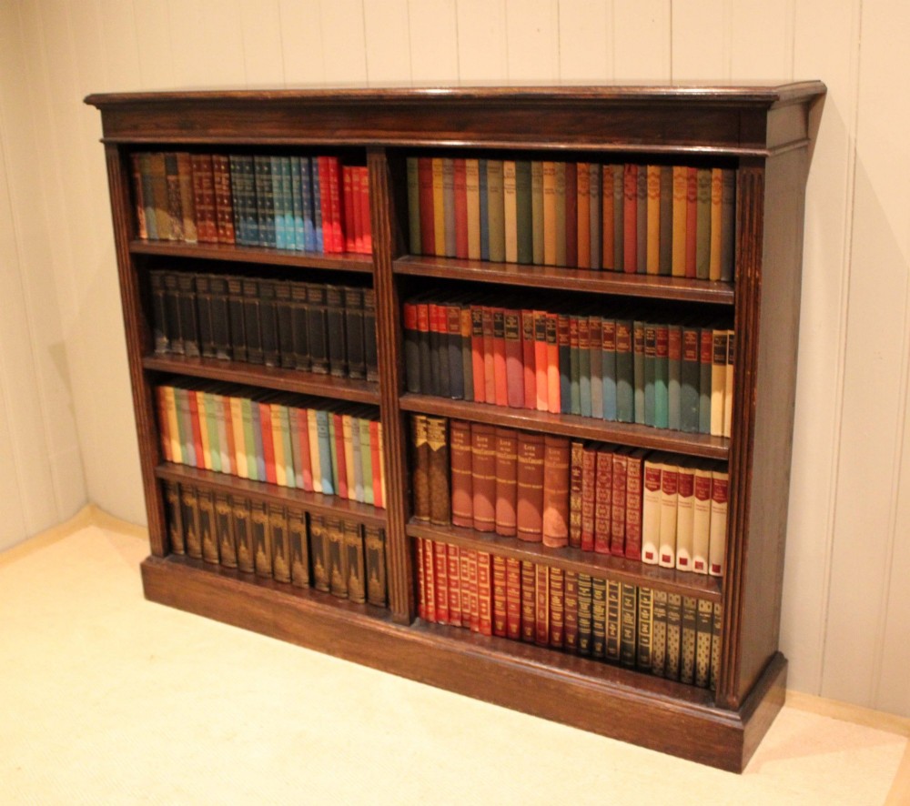 A double-bay open oak library bookcase featuring fluted pilasters, multiple horizontal shelves, a moulded top edge, and a solid plinth base. View XIII