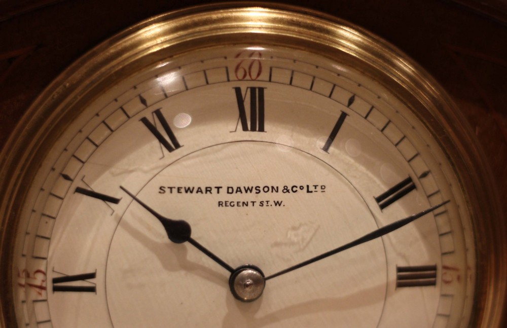 An Edwardian mahogany mantel clock featuring an arched top, brass side columns, brass feet, and a circular white dial with black Roman numerals. View VII
