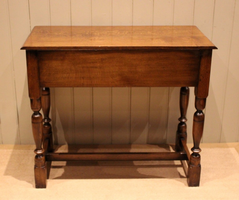 A rectangular solid oak side table featuring a quarter-sawn top, two frieze drawers with brass handles, turned legs, and an H-stretcher base. View IX