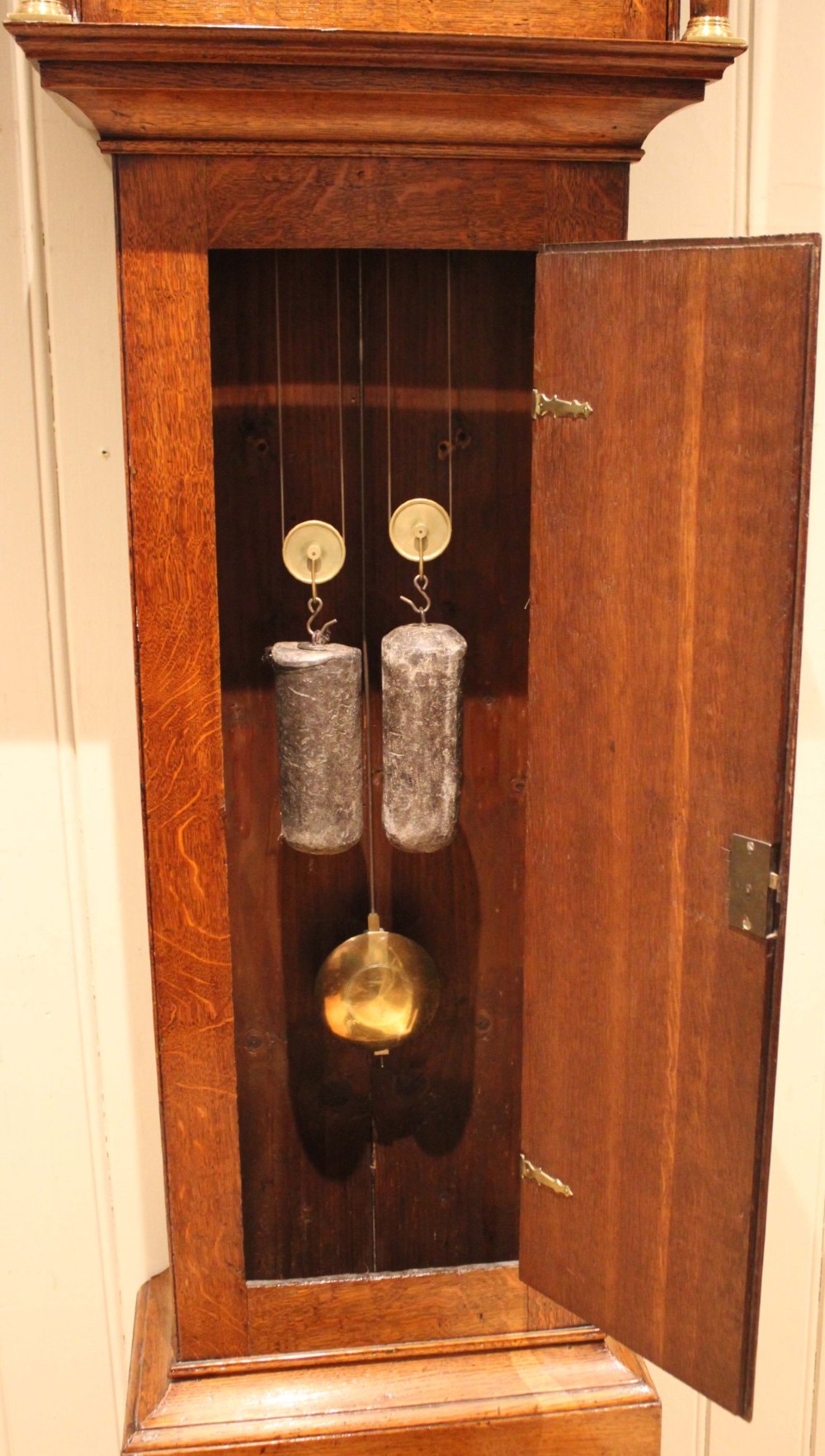 A tall late Georgian oak longcase clock featuring a square painted dial, turned hood columns, and a polished wood trunk. View VIII