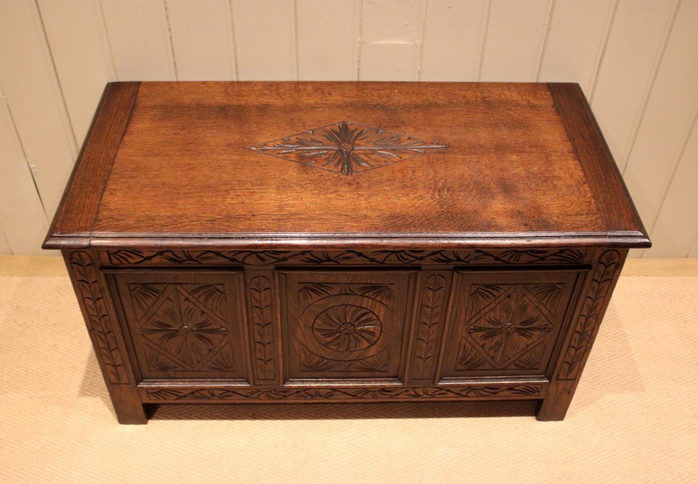 A rectangular dark oak storage coffer featuring three hand-carved front panels with rosette and geometric motifs. View II