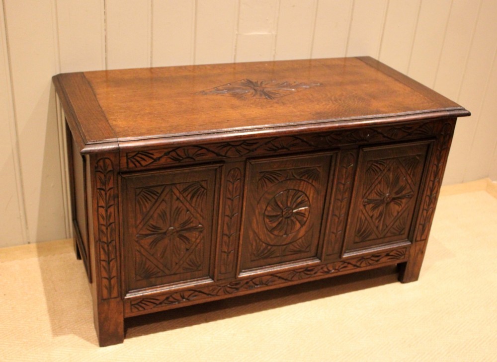 A rectangular dark oak storage coffer featuring three hand-carved front panels with rosette and geometric motifs. View III