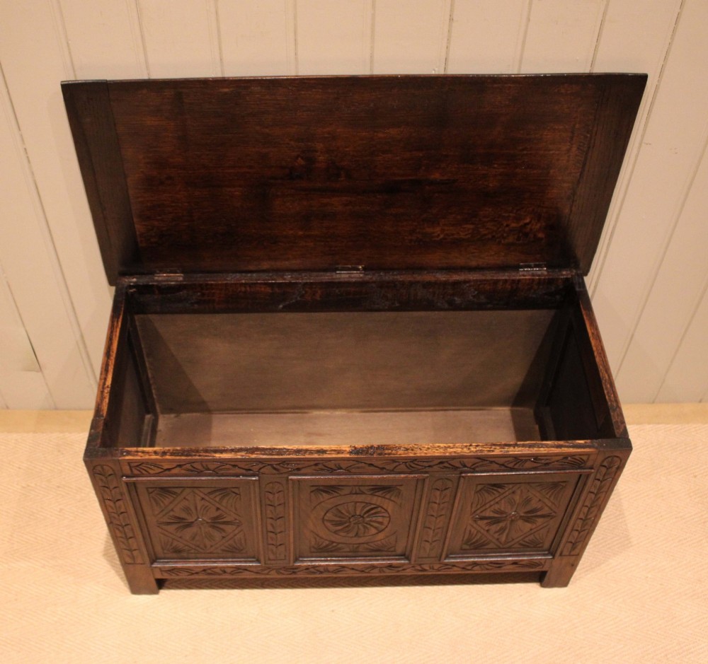 A rectangular dark oak storage coffer featuring three hand-carved front panels with rosette and geometric motifs. View VI