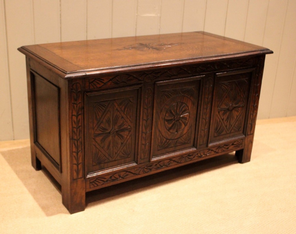 A rectangular dark oak storage coffer featuring three hand-carved front panels with rosette and geometric motifs. View VIII