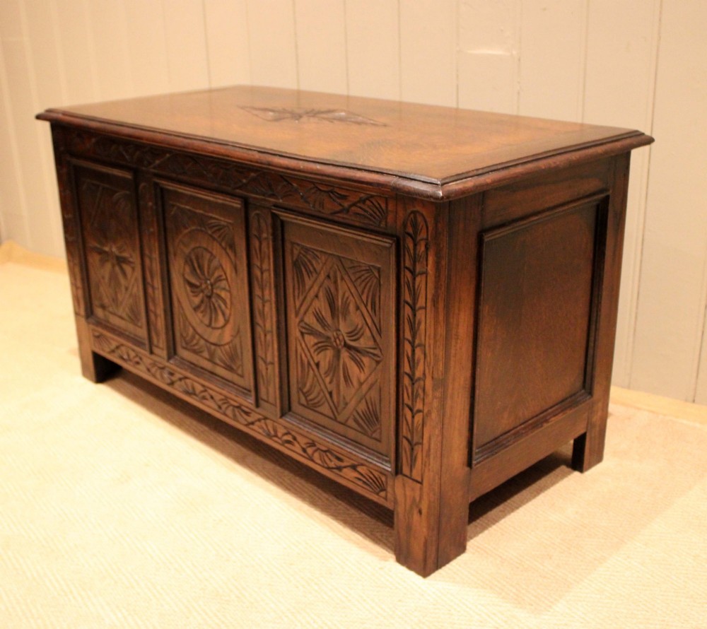 A rectangular dark oak storage coffer featuring three hand-carved front panels with rosette and geometric motifs. View IX