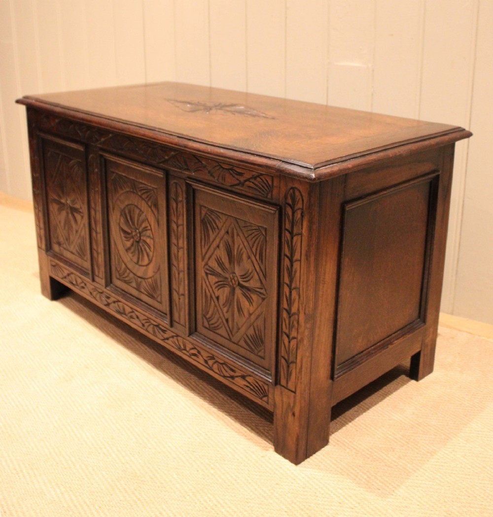 A rectangular dark oak storage coffer featuring three hand-carved front panels with rosette and geometric motifs. View XI