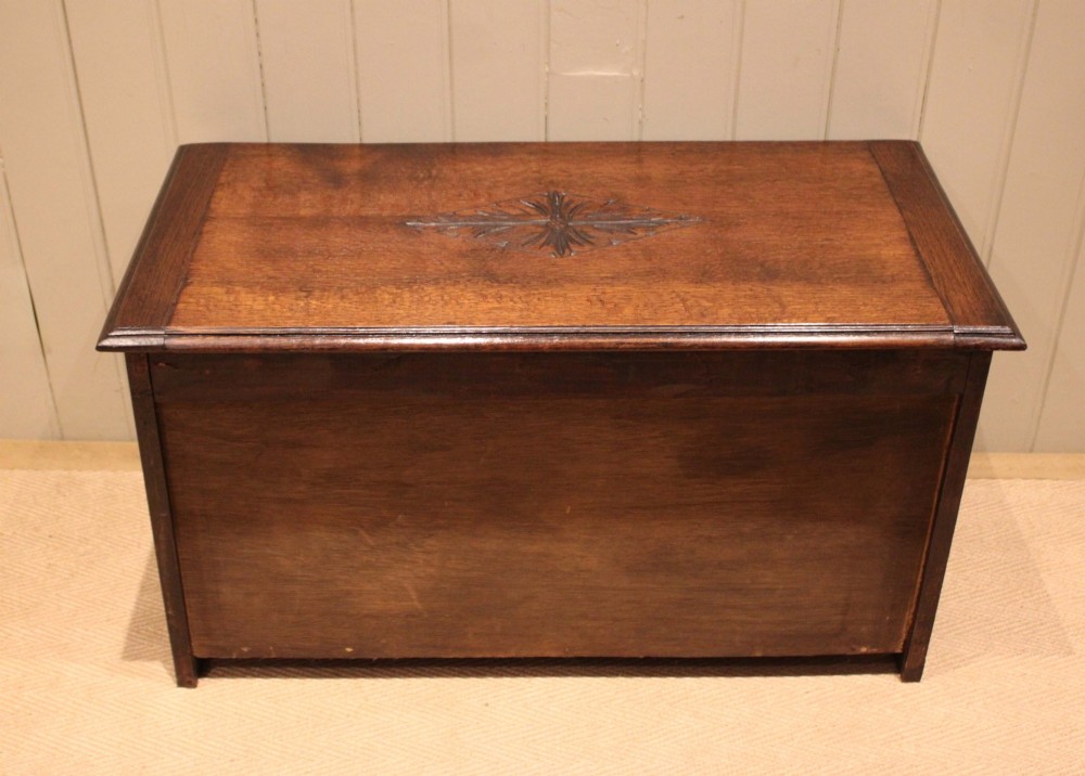 A rectangular dark oak storage coffer featuring three hand-carved front panels with rosette and geometric motifs. View XII