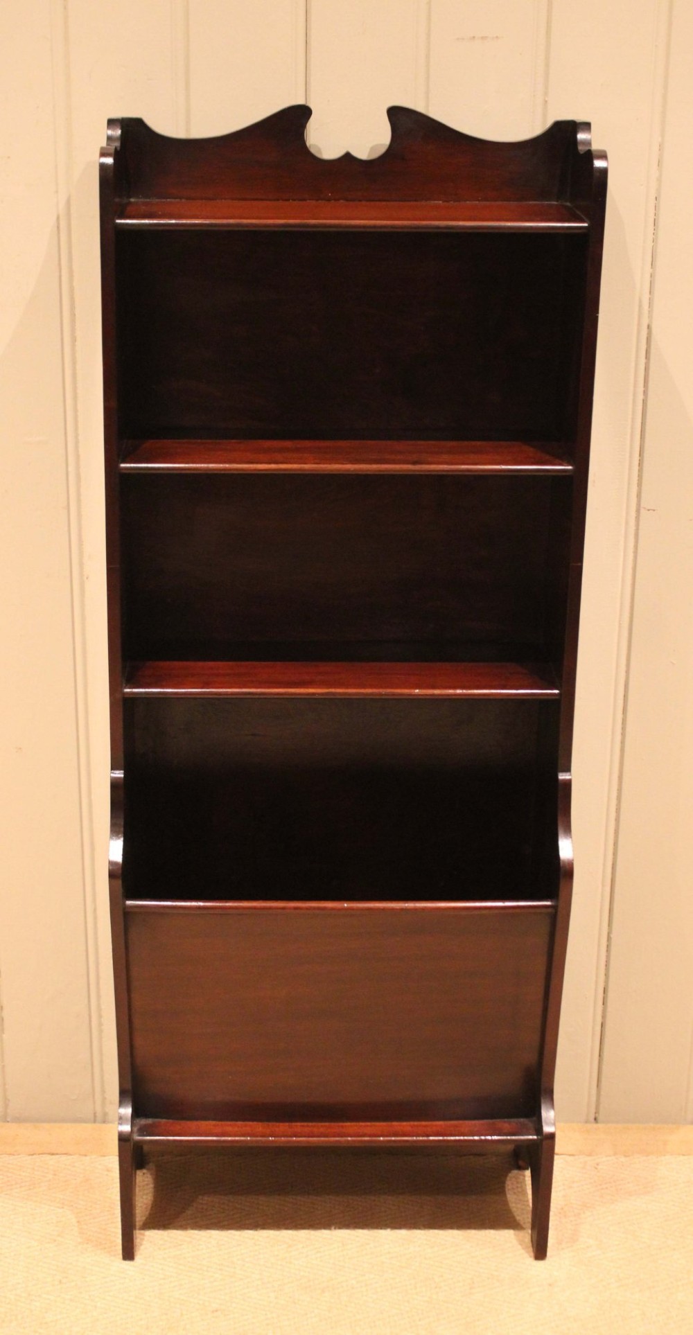 A narrow dark mahogany floor-standing shelf featuring two open upper book shelves and an angled lower magazine trough with a shaped top gallery. View IV