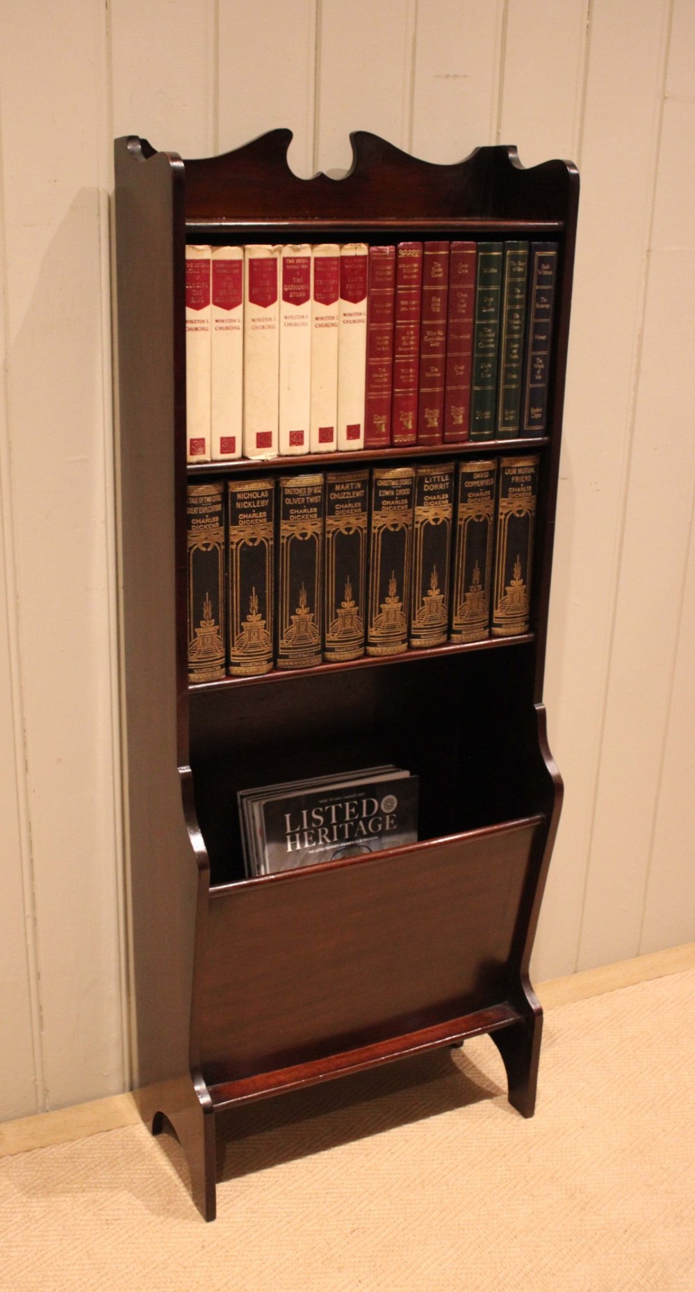 A narrow dark mahogany floor-standing shelf featuring two open upper book shelves and an angled lower magazine trough with a shaped top gallery. View V