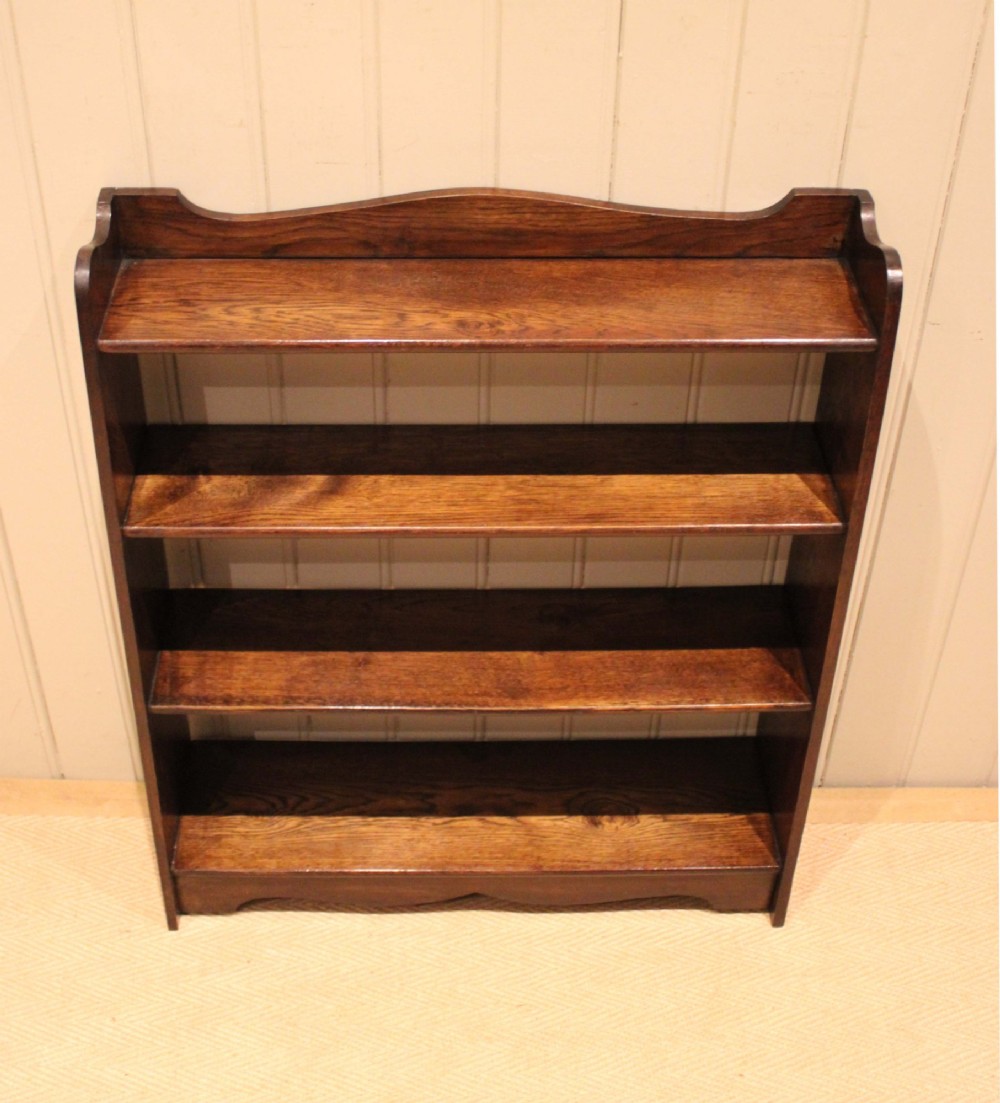 A dark oak open bookcase with three shelves filled with books, featuring a gently curved top cresting and shaped apron. View VIII