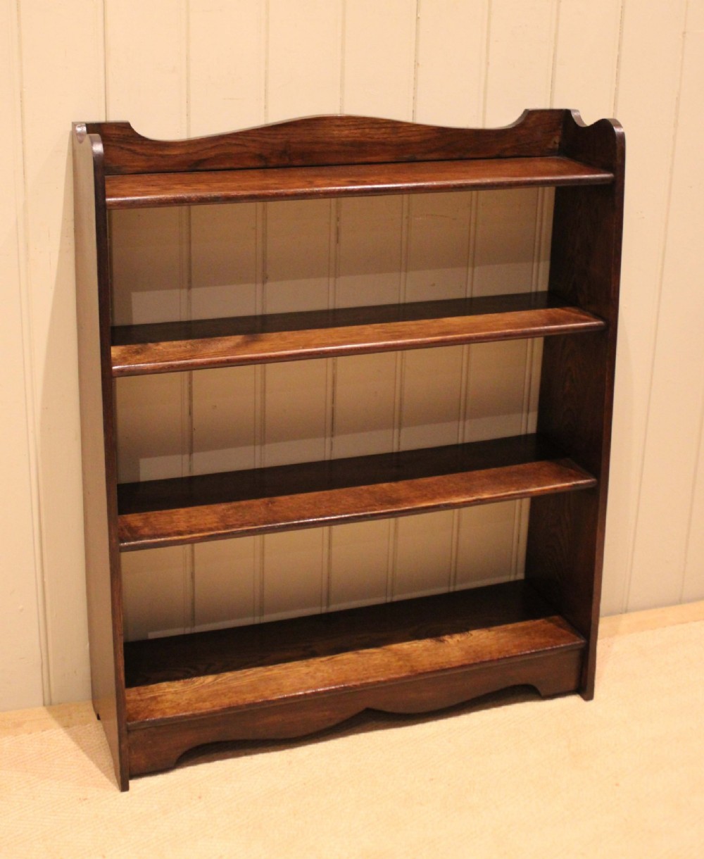 A dark oak open bookcase with three shelves filled with books, featuring a gently curved top cresting and shaped apron. View XII