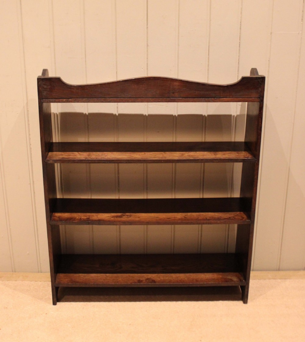 A dark oak open bookcase with three shelves filled with books, featuring a gently curved top cresting and shaped apron. View XIII