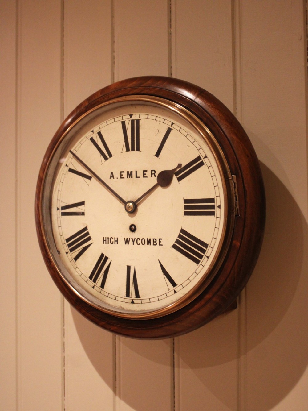 An antique circular wall clock featuring a turned dark beech frame, brass bezel, and painted white dial with Roman numerals. View II