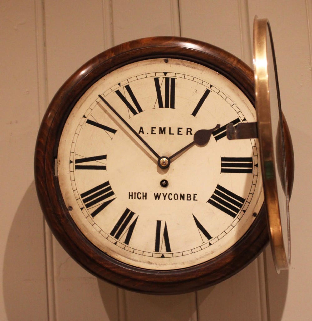 An antique circular wall clock featuring a turned dark beech frame, brass bezel, and painted white dial with Roman numerals. View VI