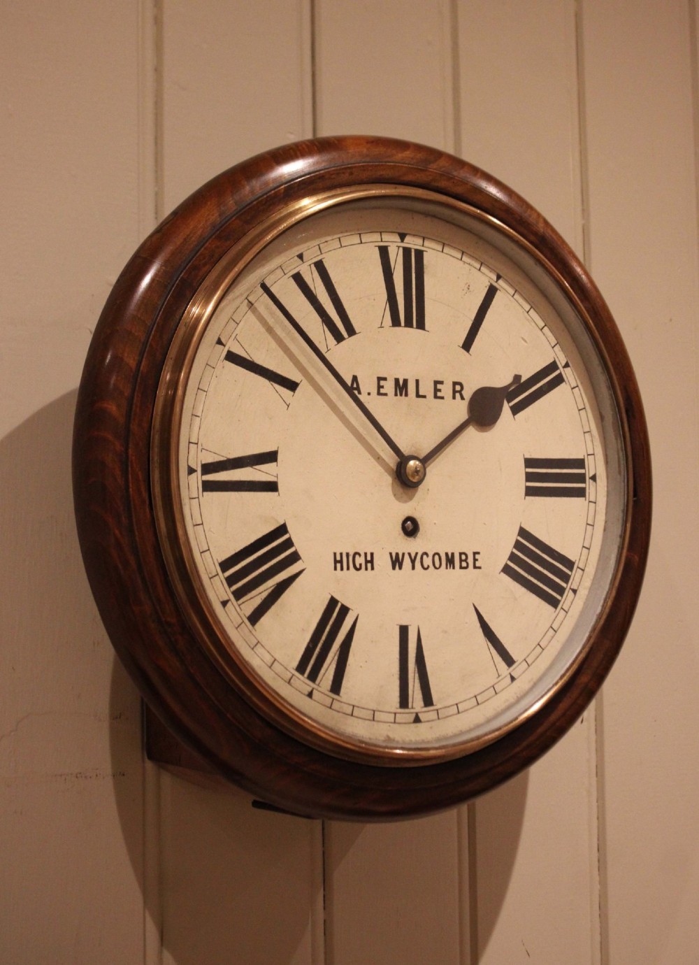 An antique circular wall clock featuring a turned dark beech frame, brass bezel, and painted white dial with Roman numerals. View IX