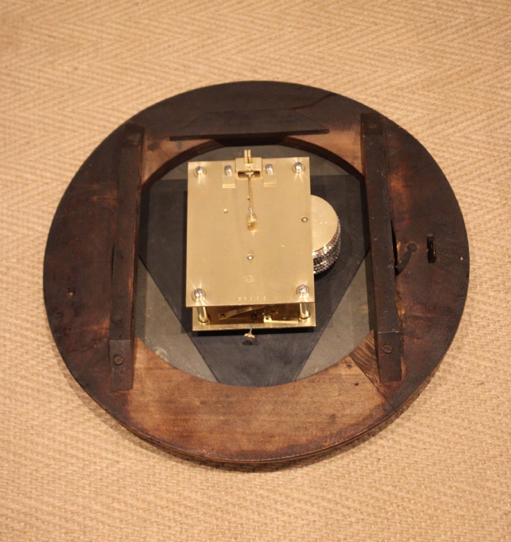 An antique circular wall clock featuring a turned dark beech frame, brass bezel, and painted white dial with Roman numerals. View X